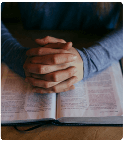 pray-hands-bible Folded hands praying over open Bible